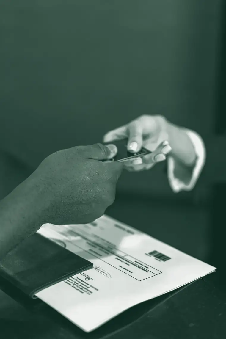 Un cliente entrega una tarjeta en el mostrador de un comercio, junto a un comprobante